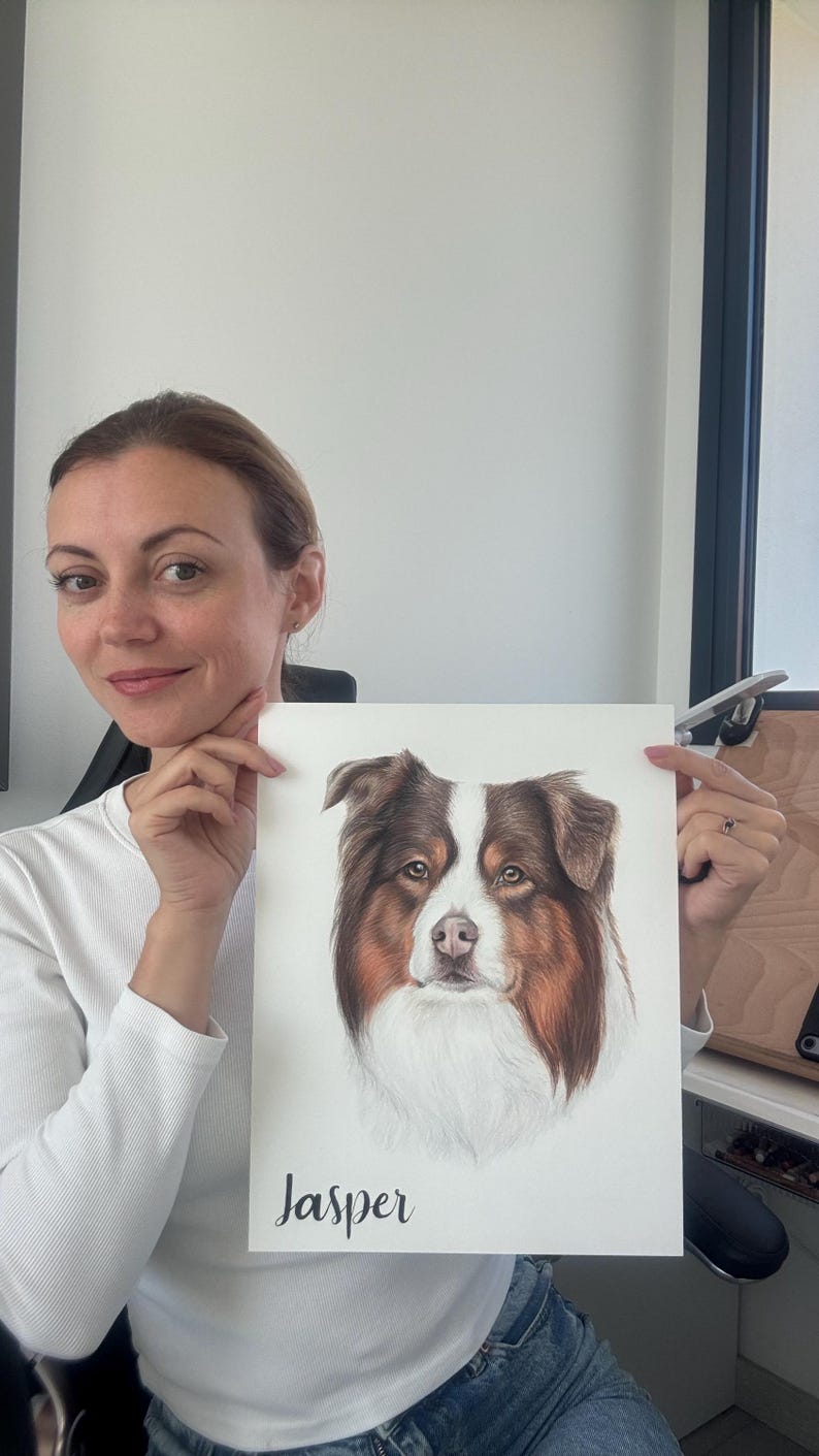 May include: A rectangular white paper print featuring a detailed colored pencil drawing of a brown, white, and tan Australian Shepherd dog. The dog's name, Jasper, is printed in black cursive script at the bottom left of the paper.