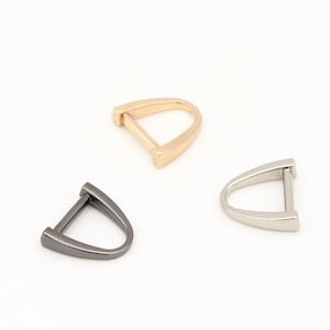 May include: Three metal D-ring hardware pieces in gold, silver, and black.
