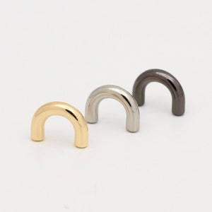 May include: Three metal cabinet pulls in gold, silver, and black finishes. Each pull is shaped like a half-circle.