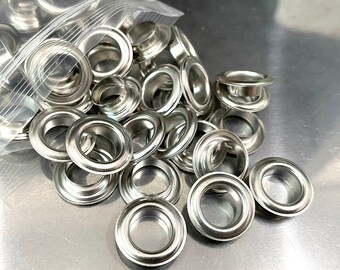 May include: A close-up of a pile of silver metal eyelets. The eyelets are in a clear plastic bag.