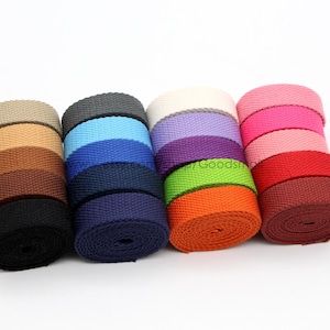 May include: A collection of 10 rolls of cotton webbing in various colors, including beige, blue, green, purple, red, and brown.