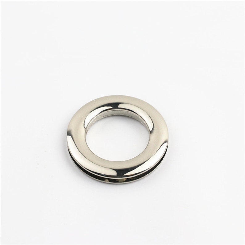 May include: A silver metal ring with a smooth, polished finish. The ring has a large inner diameter and a smaller outer diameter, creating a raised edge.