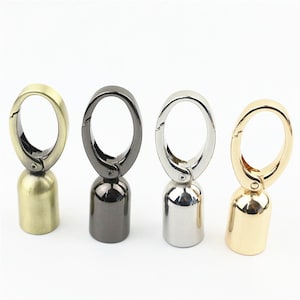 May include: Four metal swivel hooks with a bell-shaped base. The hooks are in four different finishes: antique brass, black, silver, and gold.