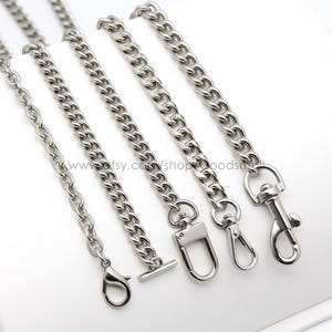 May include: Four silver chain links with different sized links and different clasps. The chains are on a white surface.