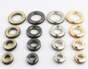 May include: Assortment of metal grommets in various sizes and finishes, including gold, silver, and black.
