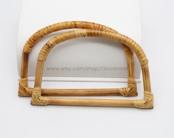 May include: Two natural woven rattan handles for a bag or purse. The handles are made of woven bamboo and are a light brown colour.
