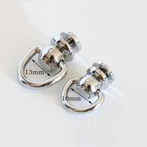 May include: Two silver swivel snap hooks with a round base. The larger hook measures 1.3 inches in diameter and the smaller hook measures 1 inch in diameter.