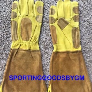 May include: A pair of yellow leather gardening gloves with brown leather palm patches and a brown leather cuff. The gloves are designed for protection and durability.  SPORTINGGOODSBYGM