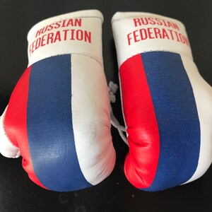 May include: A pair of white boxing gloves with the colours of the Russian flag and the text "RUSSIAN FEDERATION" on each glove.