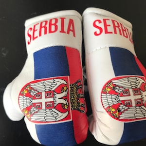 May include: A pair of white boxing gloves with the Serbian flag and the word "SERBIA" printed on them.