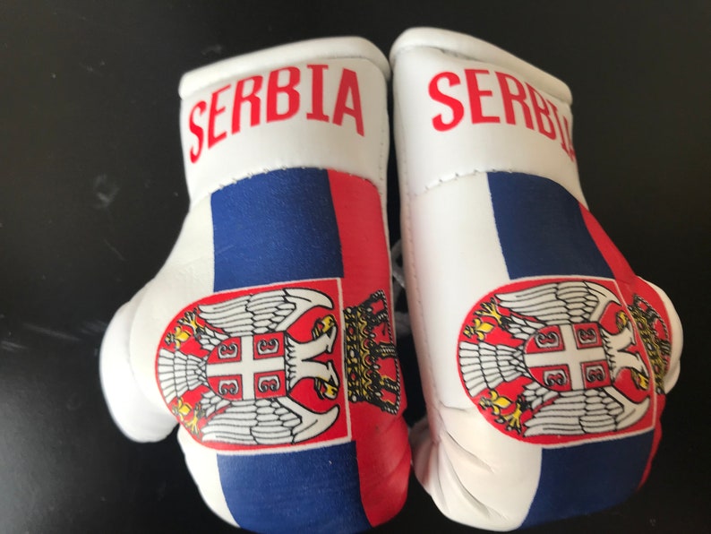 May include: A pair of white boxing gloves with the Serbian flag and the word "SERBIA" printed on them.