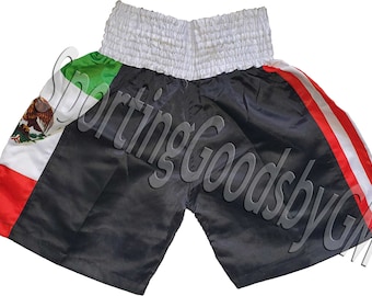 May include: Black boxing shorts with a red, white, and green Mexican flag design. The shorts have a white elastic waistband and red and white stripes on the sides.