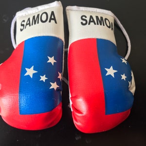 May include: A pair of red, white and blue boxing gloves with the word "SAMOA" printed on the white part of each glove. The gloves are decorated with the flag of Samoa.