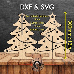 Puede incluir: Dos recortes de árboles de Navidad de madera con estrellas y puntos decorativos. Los árboles miden 300 mm de altura y están diseñados para grosores de material de 3 mm a 6,4 mm. El texto incluye "DXF & SVG" y "Laser Cutter Ready".