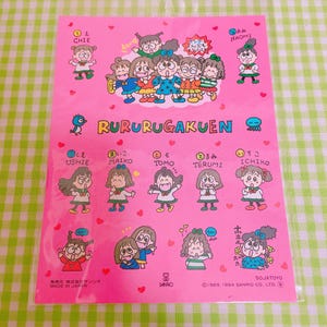 May include: A pink sticker sheet with a group of cartoon girls wearing school uniforms. The sheet features the text "Rururu Gakuen" and the names of the girls in Japanese. The sticker sheet is made in Japan.