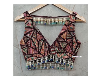 May include: A burgundy sleeveless top with a V-neck, featuring a geometric pattern in pink, green, and gold. The neckline and hem are decorated with beaded fringe in white, blue, and green, adding a touch of elegance.