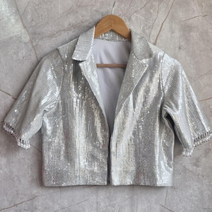 Puede incluir: Una taza de cerámica blanca con un asa negra y el texto "But First, Coffee" en negro y negrita. La taza está sobre una superficie de madera. La taza mide aproximadamente 10 cm de alto.