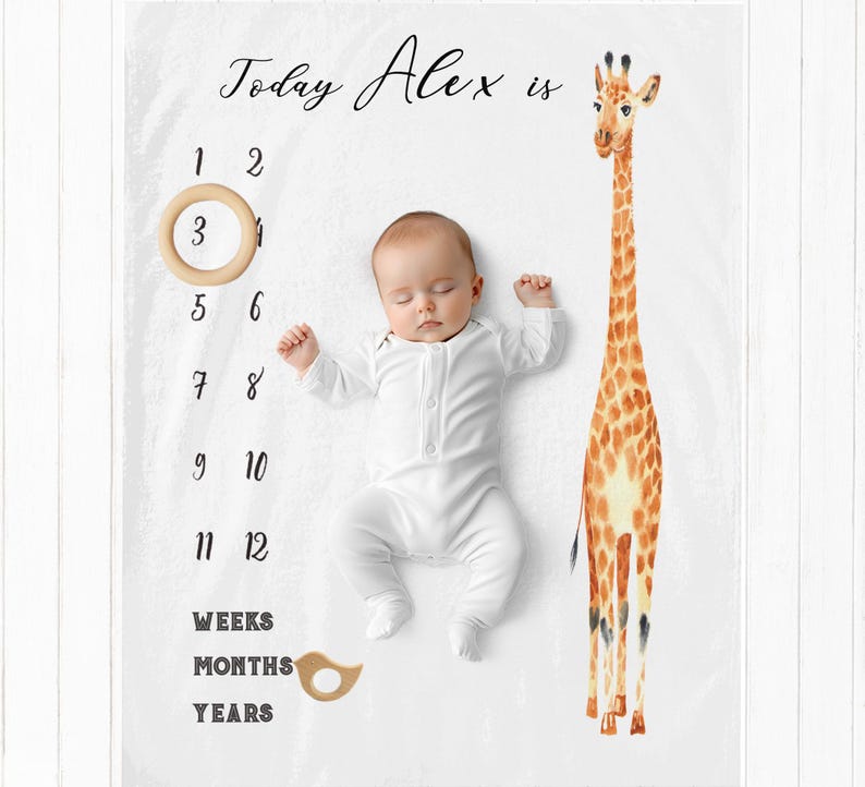 May include: A white baby milestone blanket with a giraffe illustration and the text "Today Alex is". The blanket has numbers 1 through 12, and the words "Weeks", "Months", and "Years".