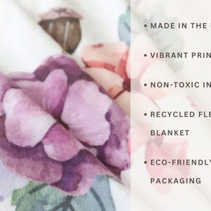 May include: A white fleece blanket with a floral print. The blanket is made in the UK with non-toxic ink and eco-friendly packaging. The text "MADE IN THE UK", "VIBRANT PRINT", "NON-TOXIC INK", "RECYCLED FLEECE BLANKET", and "ECO-FRIENDLY PACKAGING" is printed on the blanket.