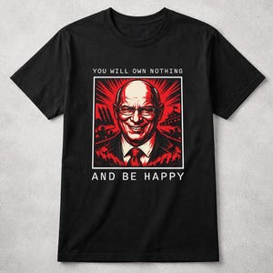 May include: Black t-shirt featuring a red and white graphic of a smiling man with the text "YOU WILL OWN NOTHING AND BE HAPPY". The graphic is framed in a white box. The shirt has short sleeves and a crew neck.