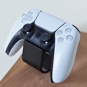 Puede incluir: Un mando inalámbrico PlayStation 5 DualSense blanco con botones negros y una base de carga negra.