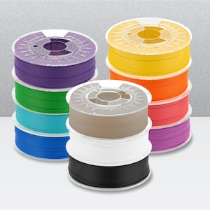 Peut inclure: Une collection de onze bobines circulaires en plastique de filament pour imprimante 3D empil&eacute;es en trois colonnes. Les bobines pr&eacute;sentent diverses couleurs unies, notamment violet, vert, bleu clair, bleu fonc&eacute;, jaune, orange, rouge, magenta, beige, blanc et noir.