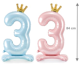 Pode incluir: Dois balões de folha em forma do número 3, um azul claro e outro rosa, cada um com uma coroa dourada. Os balões, com 84 cm de altura, são perfeitos para uma festa de terceiro aniversário.
