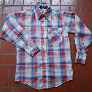 May include: A long-sleeved plaid shirt with a button-down collar. The shirt is white with red, blue, and yellow plaid.