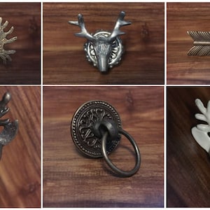 May include: Six different decorative cabinet knobs with a rustic theme. The knobs feature deer head designs in gold, silver, and white, a ring pull with an ornate design, and a simple arrow design.