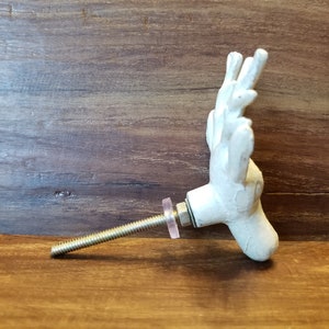 May include: White ceramic deer head door knob with a silver screw and a pink washer.