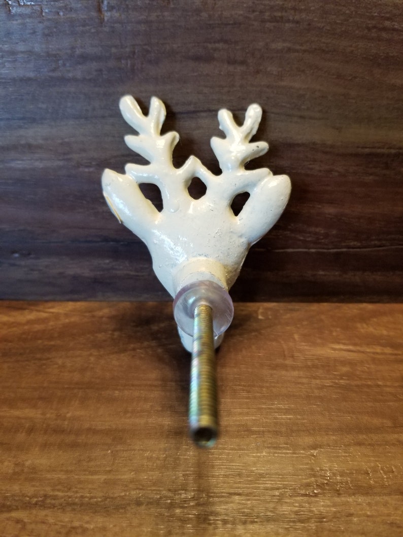 May include: White ceramic reindeer head door knob with a gold screw. The knob has a detailed design of antlers and a face.