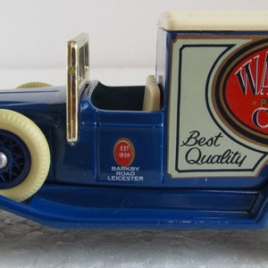 May include: A miniature dark blue delivery truck model with cream wheels and roof. The side displays the "Walkers Potato Crisps" logo in red and white. The model also features gold-colored accents and the text "Barkby Road Leicester".