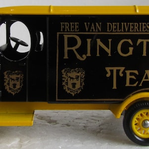 May include: A black and yellow toy delivery truck with the words "FREE VAN DELIVERIES TO ALL PARTS RINGTONS TEA" on the side.