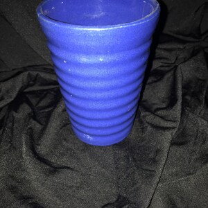 May include: A blue ceramic vase with a textured, ribbed design. The vase is empty and has a rounded top.