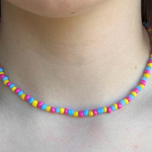 May include: A beaded necklace with alternating yellow, blue, and pink beads.