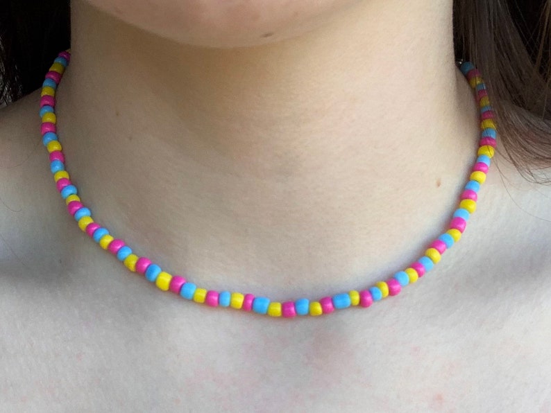 May include: A beaded necklace with alternating yellow, blue, and pink beads.