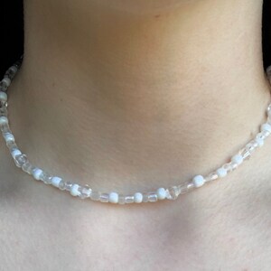 May include: A white beaded choker necklace with clear and opaque beads.