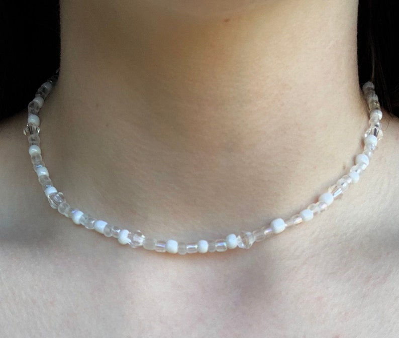 May include: A white beaded choker necklace with clear and opaque beads.