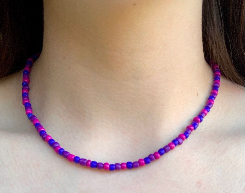 May include: A purple and pink beaded necklace. The beads are small and round, and they are arranged in a repeating pattern of purple and pink.
