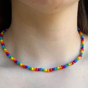 May include: A rainbow beaded necklace with small, round beads in red, orange, yellow, green, blue, indigo, and violet.