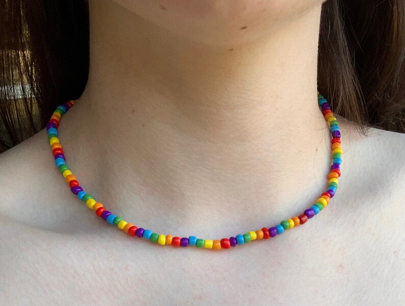 May include: A rainbow beaded necklace with small, round beads in red, orange, yellow, green, blue, indigo, and violet.