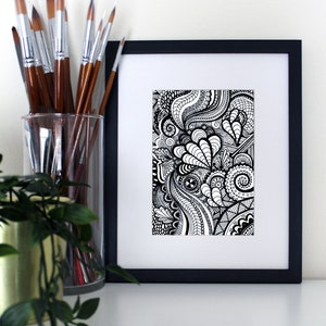 May include: A black and white framed print of a detailed abstract design with swirling lines and patterns.