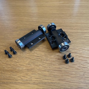 May include: Two black 3D printed roller assemblies with silver bearings and black screws.