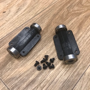 May include: Two black plastic 3D printed roller bearing mounts with silver bearings and a set of black screws.