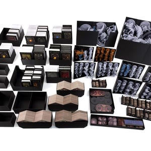 Könnte beinhalten: Eine Sammlung schwarzer Aufbewahrungsboxen und -schalen, gefüllt mit Spielkomponenten. Das Bild zeigt verschiedene Behälter mit Karten, Miniaturfiguren und anderen Spielteilen, ideal zum Organisieren von Brettspielzubehör.