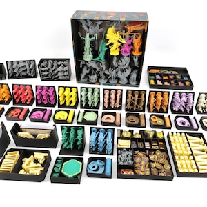 Könnte beinhalten: Ein Satz schwarzer Plastik-Aufbewahrungsboxen mit Trennwänden zum Organisieren von Brettspielteilen. Die Boxen sind gefüllt mit bunten Plastikminiaturen, Würfeln und anderen Spielkomponenten.