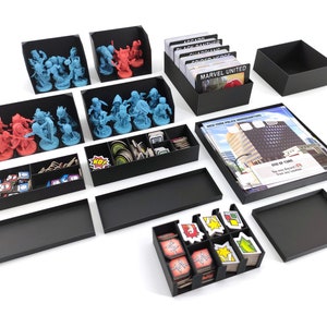 Könnte beinhalten: Ein Satz schwarzer Schaumstoffeinsätze zum Organisieren eines Brettspiels. Die Einsätze enthalten Fächer zum Verstauen von Karten, Spielsteinen und Miniaturen. Die Einsätze sind mit dem Titel des Spiels "Marvel United" beschriftet.