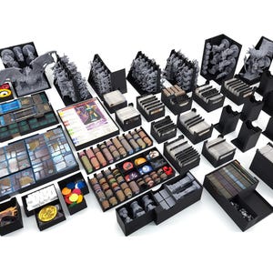 Puede incluir: Un organizador de juegos de mesa negro y gris con múltiples compartimentos para guardar las piezas del juego, las cartas y los dados. El organizador está diseñado para adaptarse a un juego de mesa específico y ayuda a mantener el juego organizado y fácil de transportar.