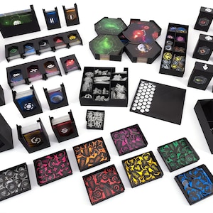 May include: An assortment of black game organizers and components, including card holders, token trays, and hexagonal game board tiles. The components are filled with cards, tokens, and miniature game pieces in various colors.
