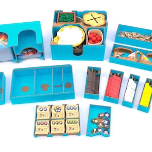 May include: A selection of teal-coloured game organisers and components. The set includes various trays and boxes containing game pieces, cards, and tokens. Some boxes hold miniature food items, while others contain wooden game pieces. The game appears to be a board game.